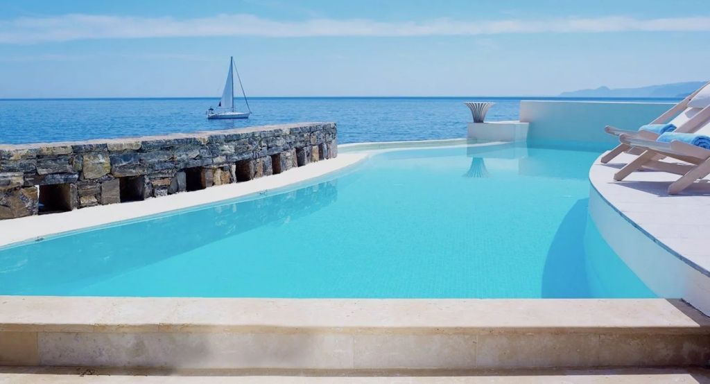 Infinity-Pool mit Blick auf das Meer und einem Segelboot am Horizont