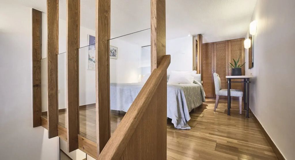 Elegant eingerichtetes Schlafzimmer in der Odysseas 1 Klub Suite mit Holztreppe.