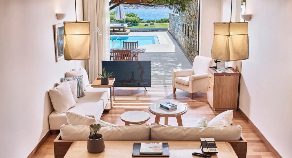 Luxuriöses Wohnzimmer mit Blick auf den Pool und das Meer in der Odysseas 1 Klub Suite.