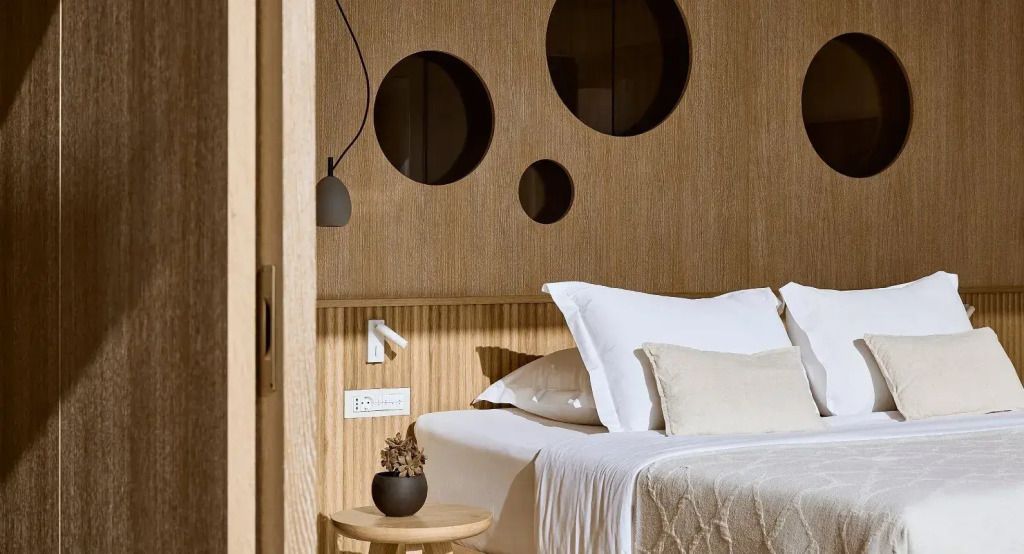 Minimalistisch eingerichtetes Schlafzimmer mit Holzwänden und runden Fenstern.