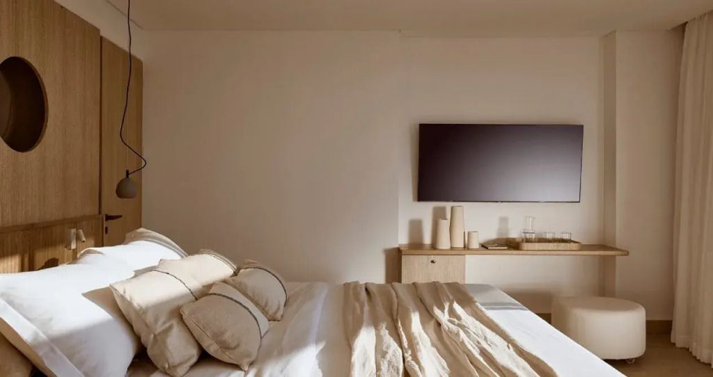 Geräumiges Schlafzimmer mit großen Kissen und flachem Fernseher an der Wand.