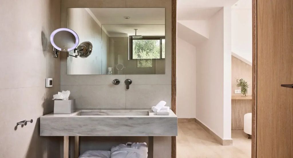 Modernes Badezimmer mit großem Spiegel und Natursteinwaschbecken.