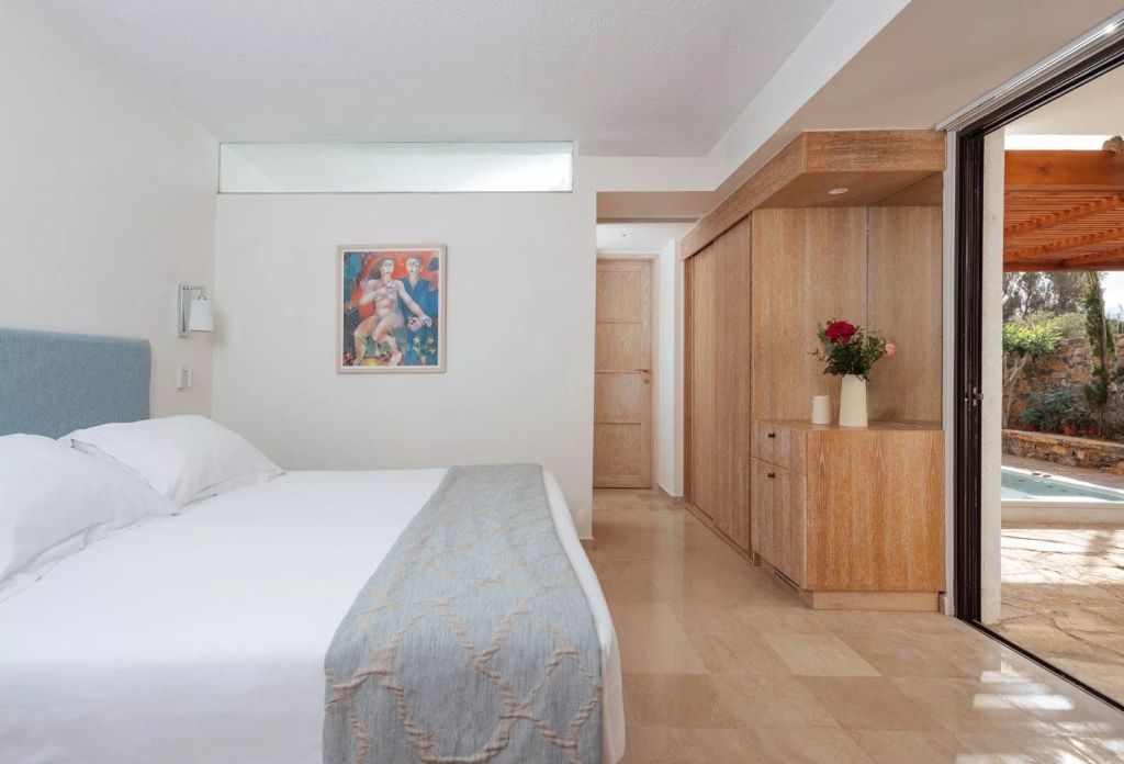 Helles Schlafzimmer mit Kunstwerk an der Wand und weißen Bettbezügen