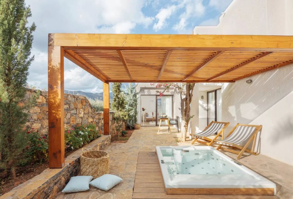 Privater Gartenbereich mit Whirlpool und Liegestühlen unter einer hölzernen Pergola