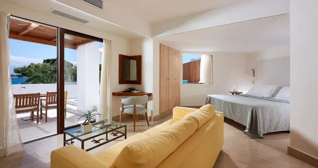Geräumige Suite mit gelbem Sofa und Schreibtisch mit Blick auf die Terrasse