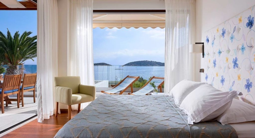 Helles Zimmer mit Doppelbett und Meerblick durch große Fenster