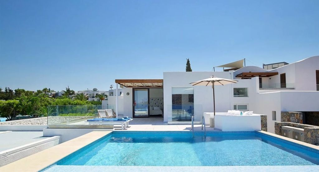Privater Pool vor moderner Villa mit Sonnenschirmen und Liegen