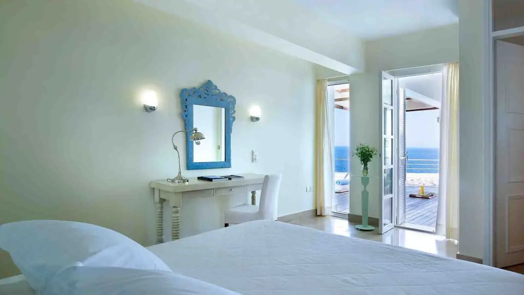 Helles Schlafzimmer mit blauem Spiegel und Balkon mit Meerblick