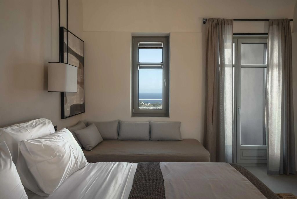 Helles Zimmer mit großem Bett und Meerblickfenster im Stamna Sifnos Hotel.
