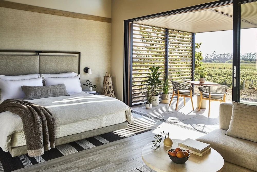 Modernes Hotelzimmer mit Doppelbett und Terrasse mit Gartenblick