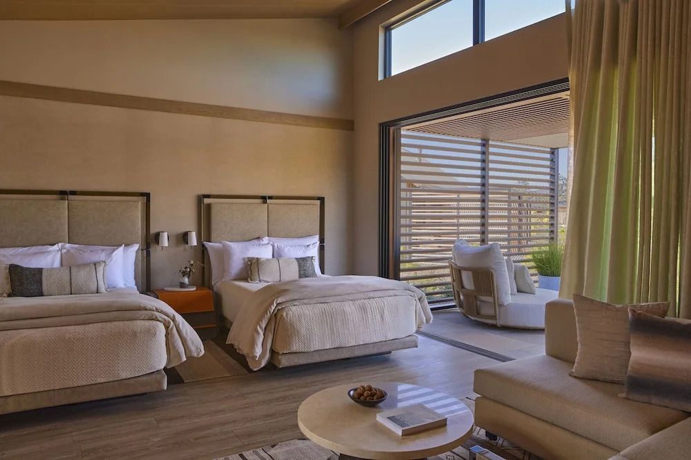Modernes Hotelzimmer mit zwei Doppelbetten und Sitzecke