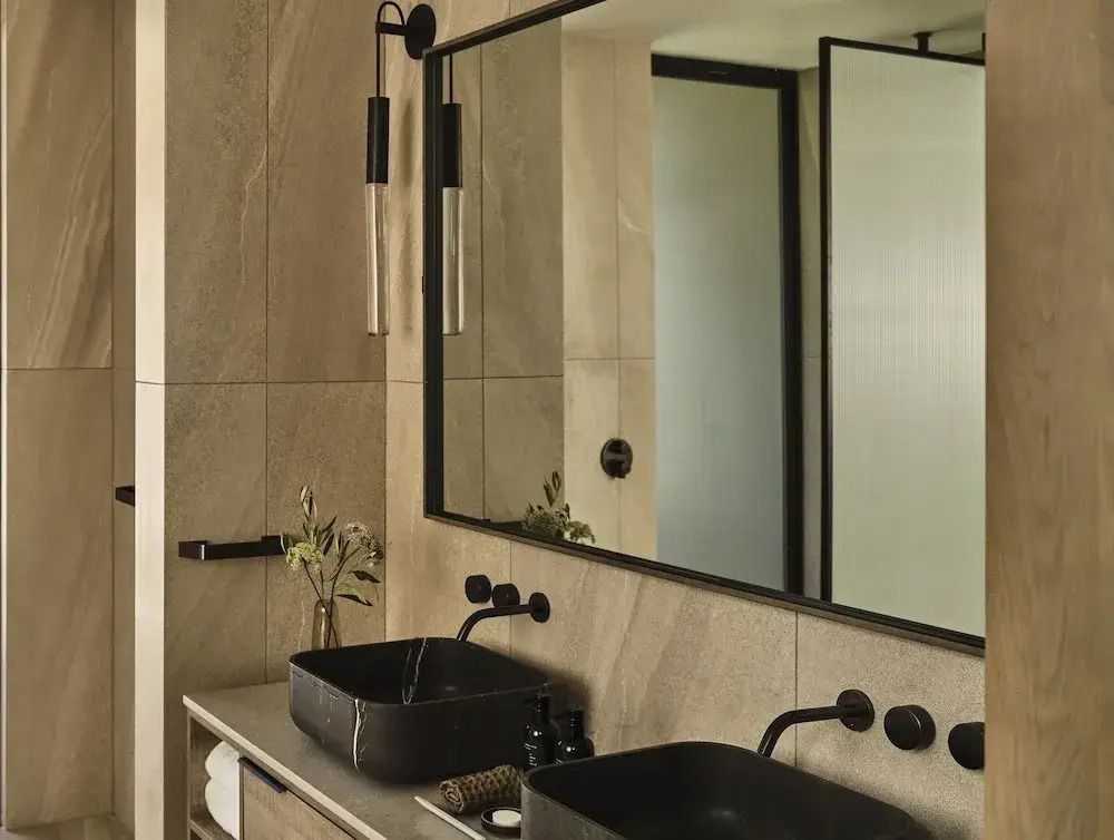 Modernes Badezimmer mit Doppelwaschbecken und großer Spiegelwand.