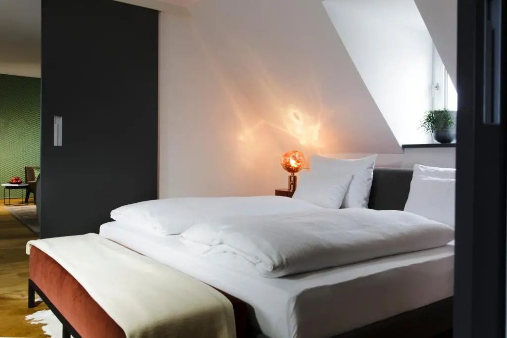 Gemütliches Schlafzimmer in der Deluxe Suite mit moderner Beleuchtung und Dachfenster
