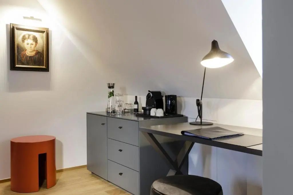 Arbeitsbereich in der Deluxe Suite mit Schreibtisch, Kaffeemaschine und stilvoller Lampe