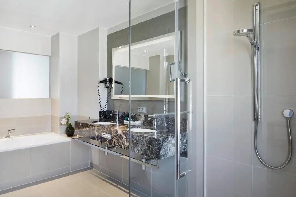 Elegantes Badezimmer mit modernem Waschbecken und Glasdusche in der Executive Suite
