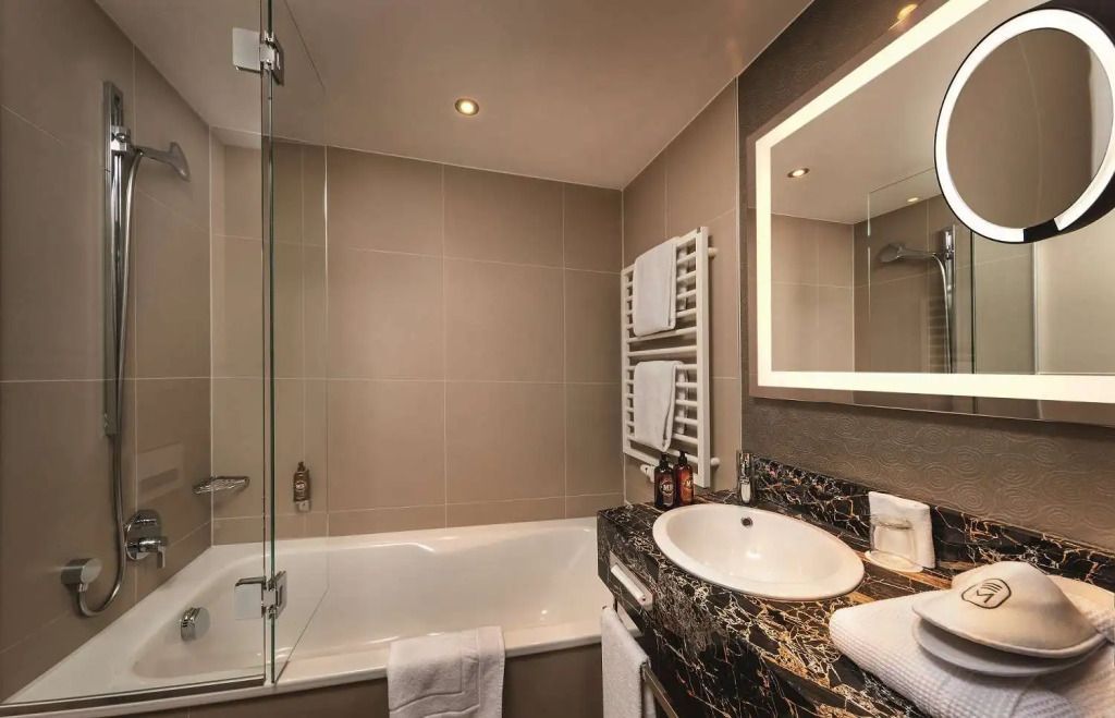 Badezimmer mit Badewanne und beleuchtetem Spiegel