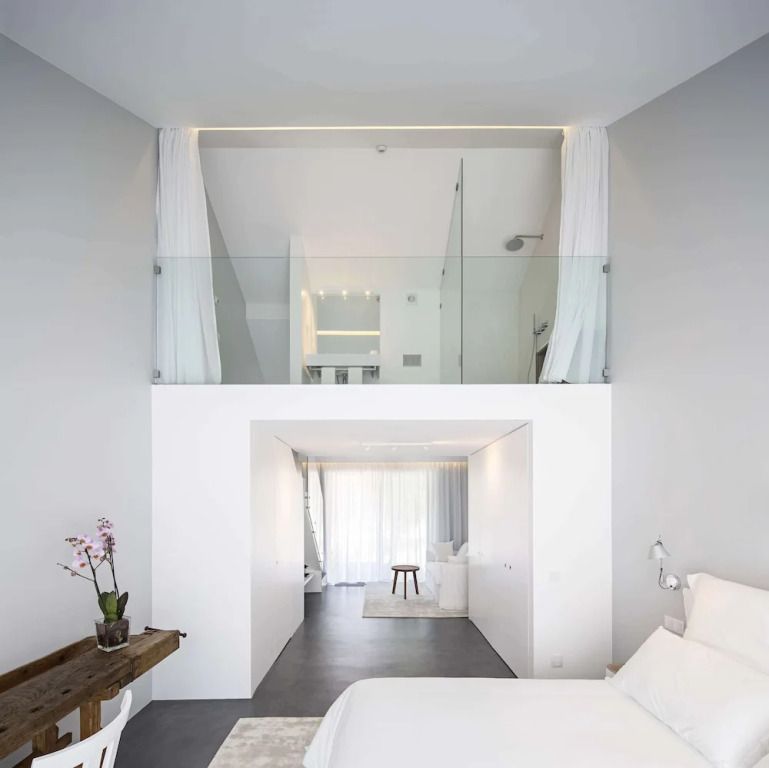 Modernes Doppelzimmer mit hohen Decken und weißem Interieur, Ausblick in den Garten.