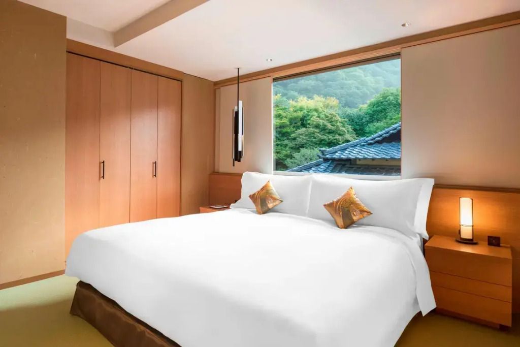 Helles Doppelzimmer mit großem Bett und Blick auf grüne Landschaft.