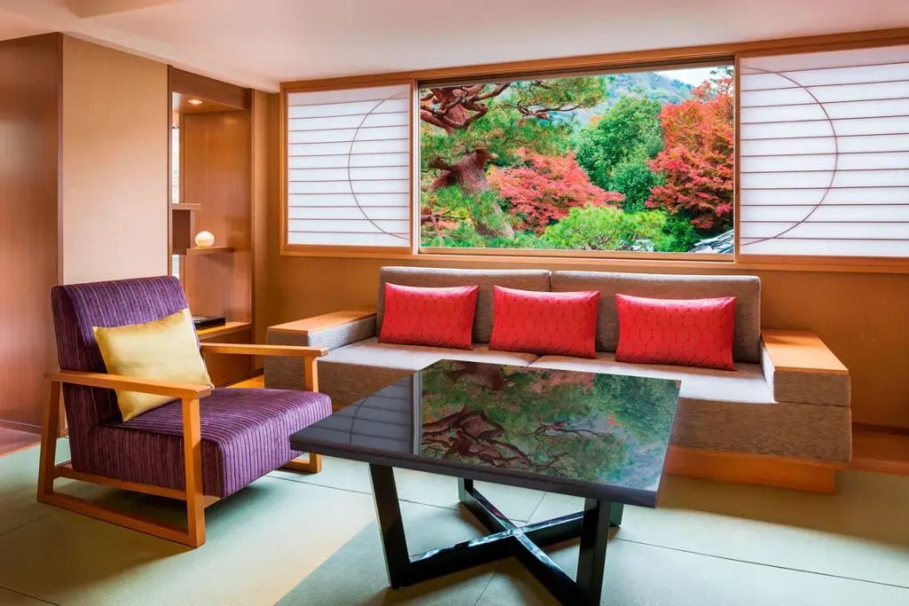 Loungebereich mit Sofa und Panoramafenster, Blick auf Herbstfarben.