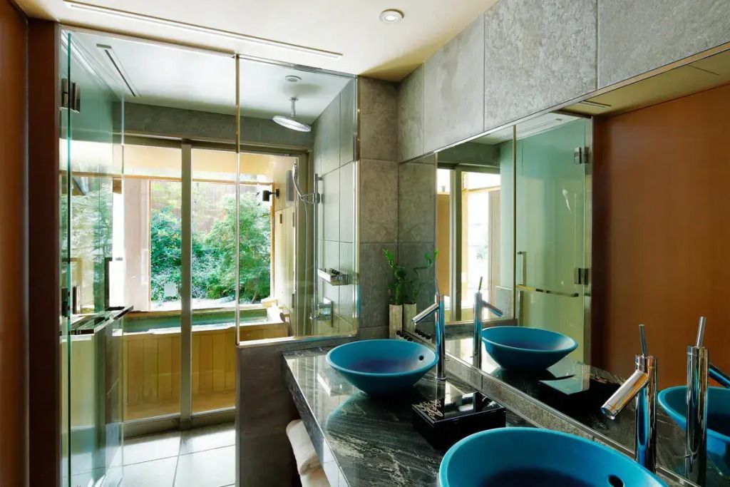 Modernes Badezimmer mit Waschbecken aus blauer Keramik und Blick ins Grüne
