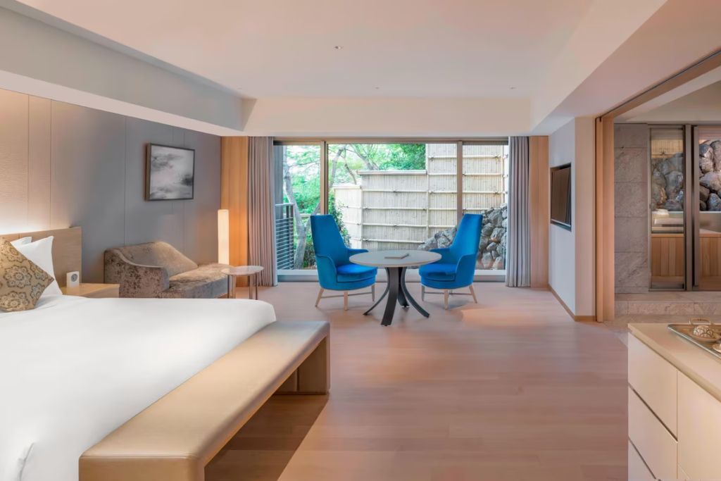 Geräumiges Zimmer mit Doppelbett, Sitzbereich und Zugang zu einem privaten Garten