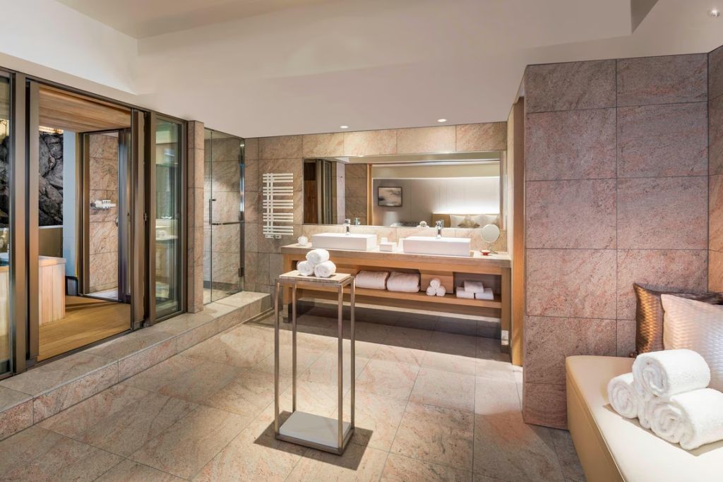 Luxuriöses Badezimmer mit Doppelwaschbecken, großen Spiegeln und glatten Steinoberflächen