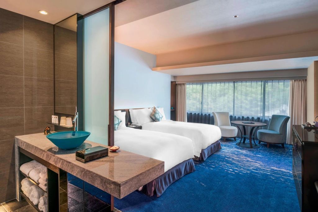 Elegantes Hotelzimmer mit zwei Einzelbetten, blauem Teppich und moderner Einrichtung