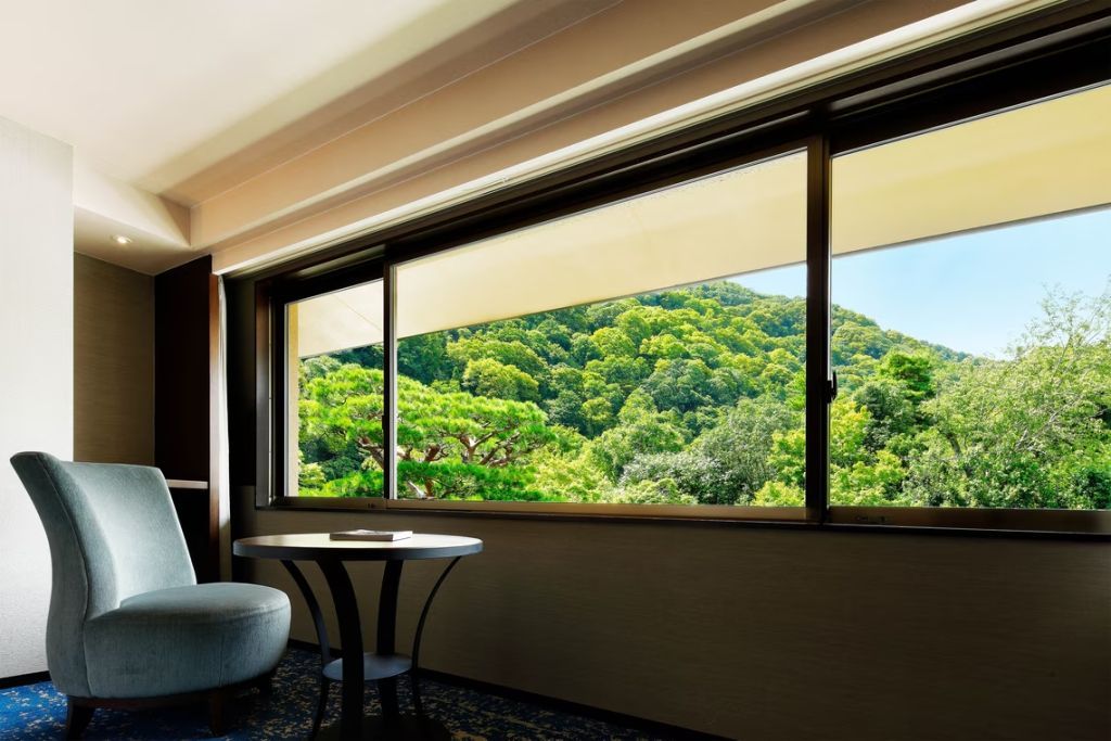 Großes Fenster mit Blick auf grüne Hügel und Bäume