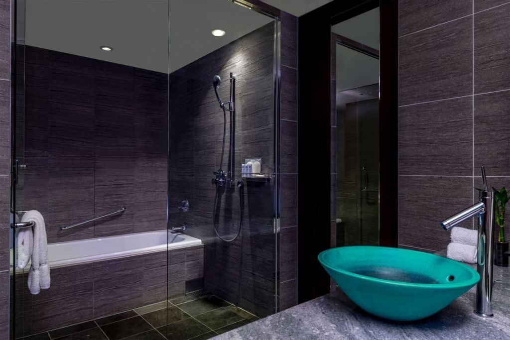 Modernes Badezimmer mit Glasdusche, Badewanne und türkisfarbenem Waschbecken