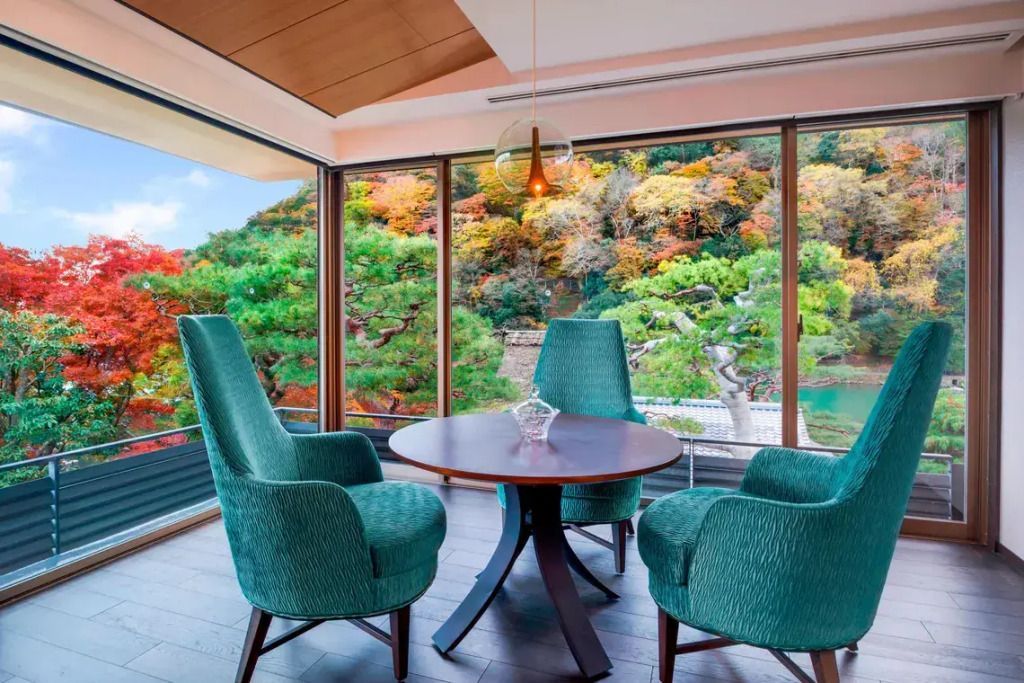 Sitzbereich im Zimmer mit Panoramablick auf farbenfrohe Herbstlandschaft.