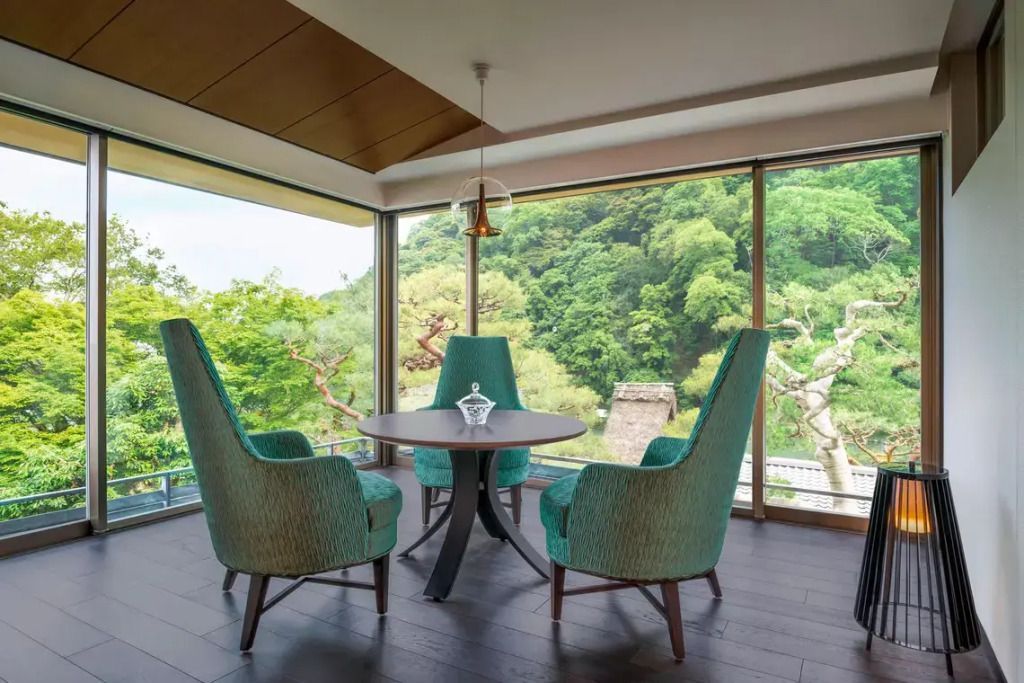 Zimmer mit großen Fenstern und Ausblick auf grüne Landschaft und Fluss.