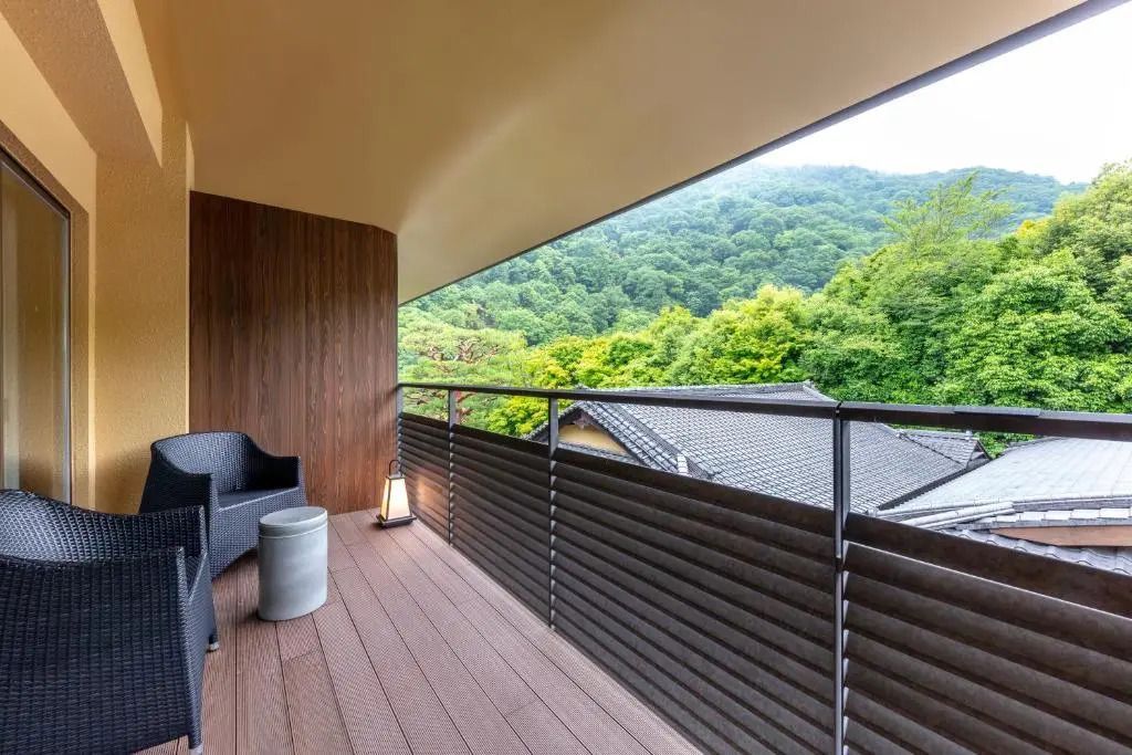 Großer Balkon mit Sitzgelegenheiten und Blick auf üppigen Wald.
