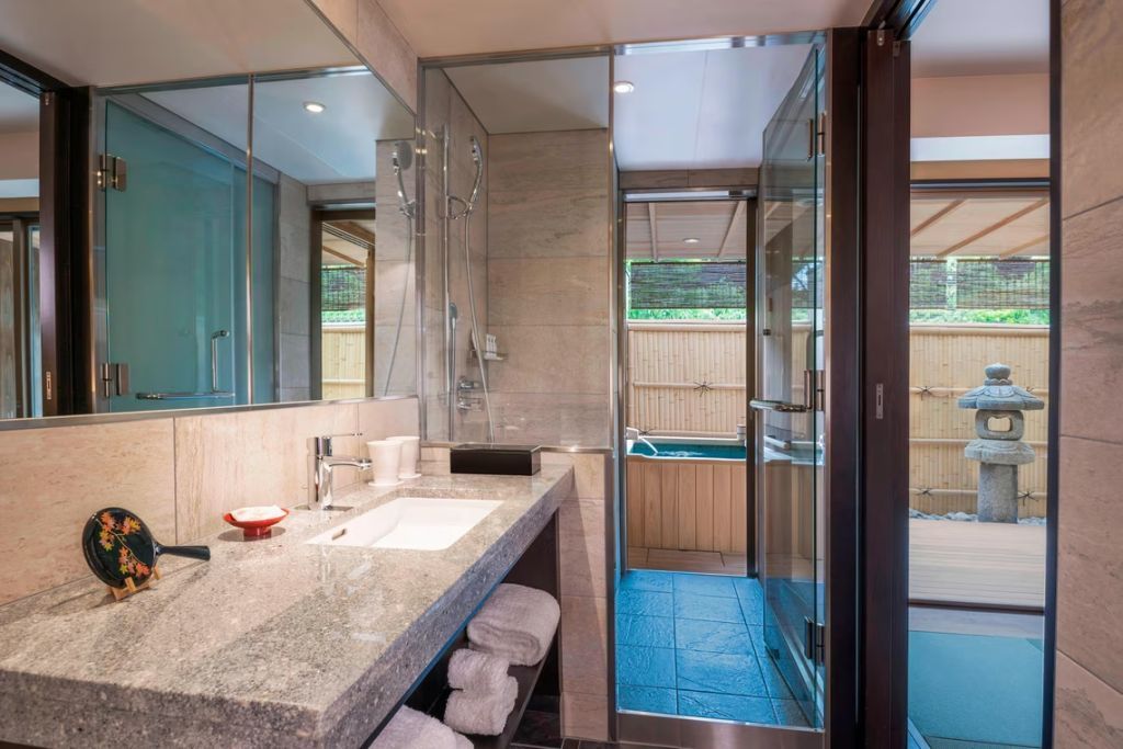 Modernes Badezimmer mit großem Waschtisch und Zugang zu einem privaten Außenbereich mit Badewanne.