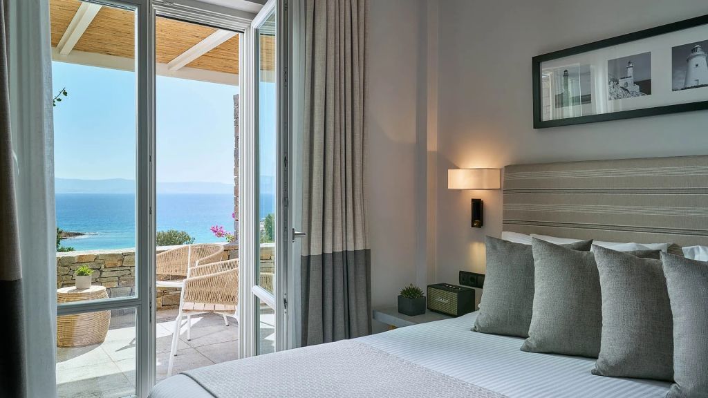 Modernes Doppelzimmer mit Blick auf das Meer durch offene Terrassentüren.
