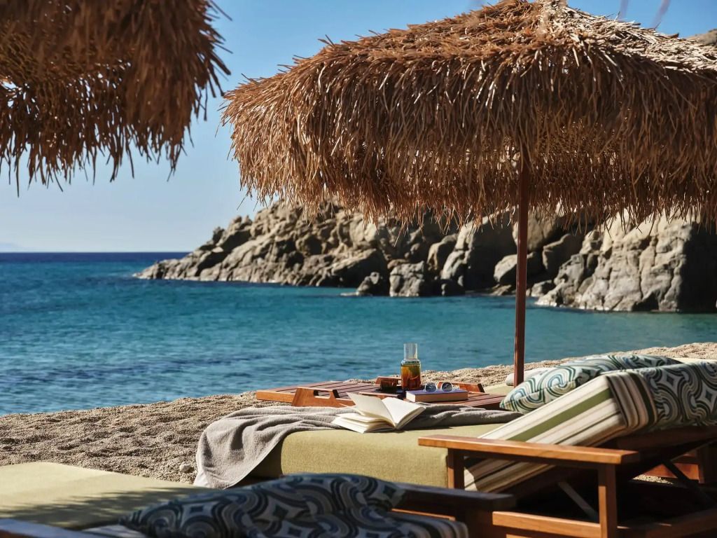 Strandbereich mit stilvollen Liegen und Strohdächern am blauen Meer
