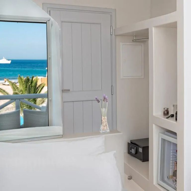 Helles Hotelzimmer mit Balkonblick auf das Meer und stilvollem Interieur