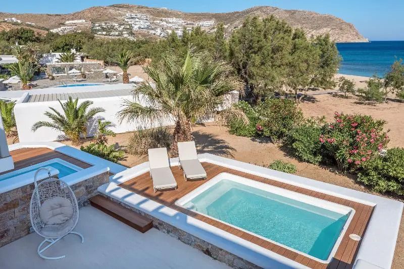 Blick auf Hotelanlage mit kleinem Pool und Sonnenliegen umgeben von grüner Landschaft