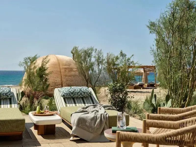 Terrasse mit Liegestühlen und Kakteengarten mit Meerblick im Hintergrund.