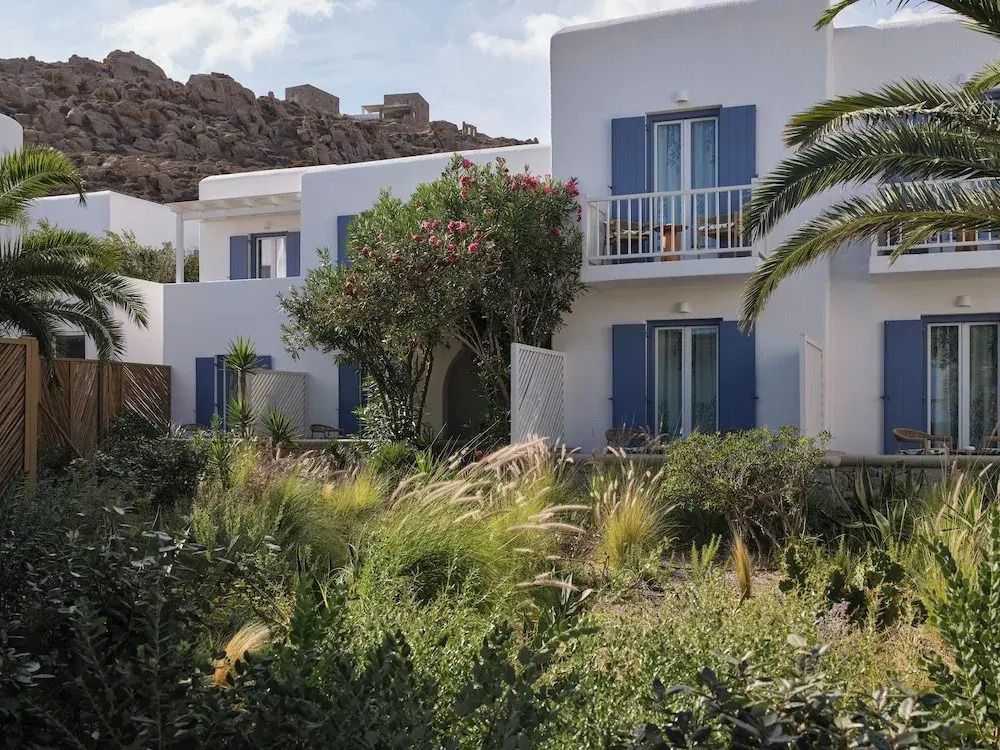 Hotelgebäude mit natürlicher mediterraner Vegetation und blauen Fensterläden
