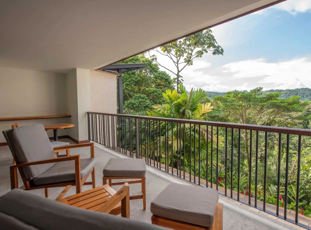 Balkon mit gemütlichen Sitzmöbeln und Blick auf den üppigen tropischen Wald.