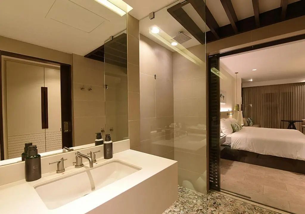 Badezimmer mit Waschbecken aus weißem Marmor und Glasabtrennung