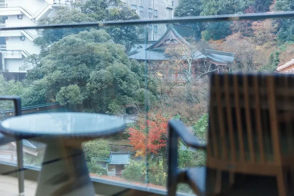 Aussicht von einem Balkon auf einen grünen Garten mit traditionellem Gebäude