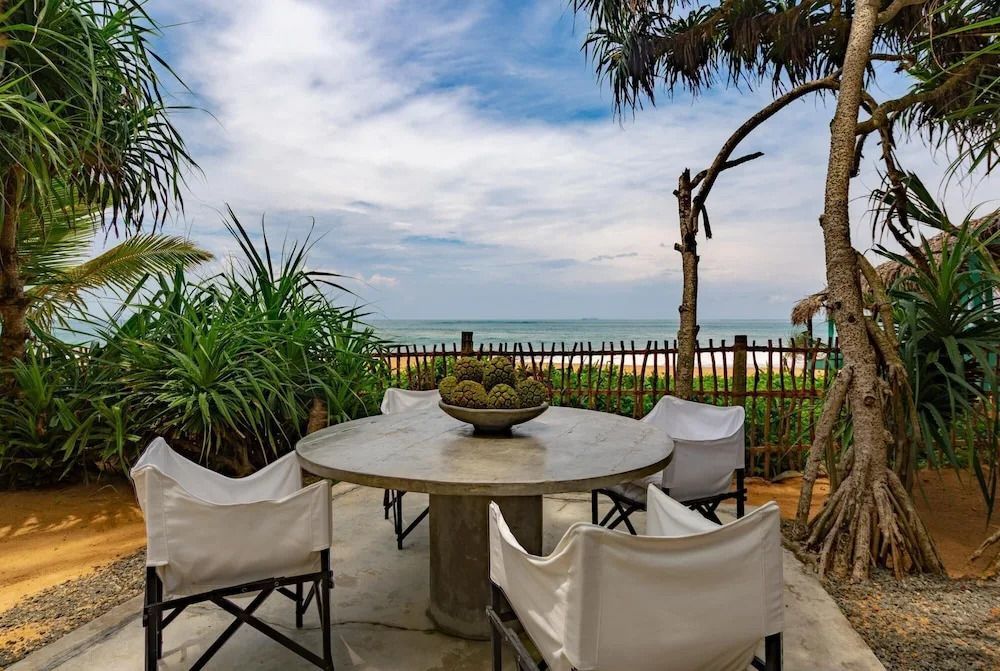 Terrasse mit Tisch und Stühlen vor Meerblick