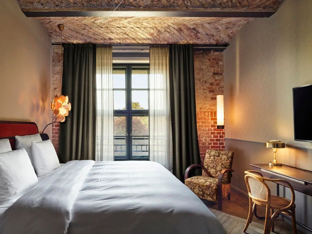 Gemütliches Doppelzimmer mit freiliegenden Backsteinwänden und großem Fenster