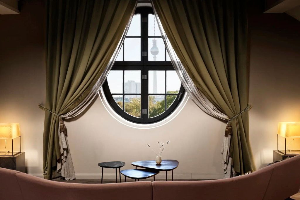 Rundes Fenster mit Ausblick auf den Fernsehturm und eleganter Vorhangdekoration