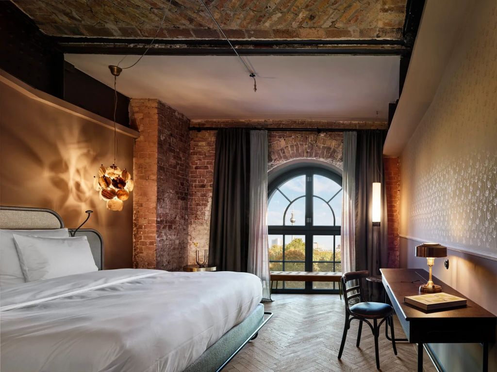 Zimmer mit großem Bett, rustikalen Wänden und einem Fenster mit Rundbogenblick
