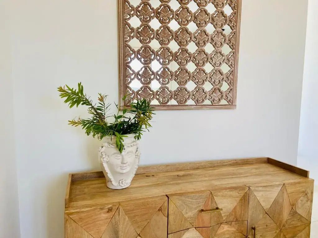 Elegante Kommode mit Pflanzenvase und dekorativem Spiegel an der Wand
