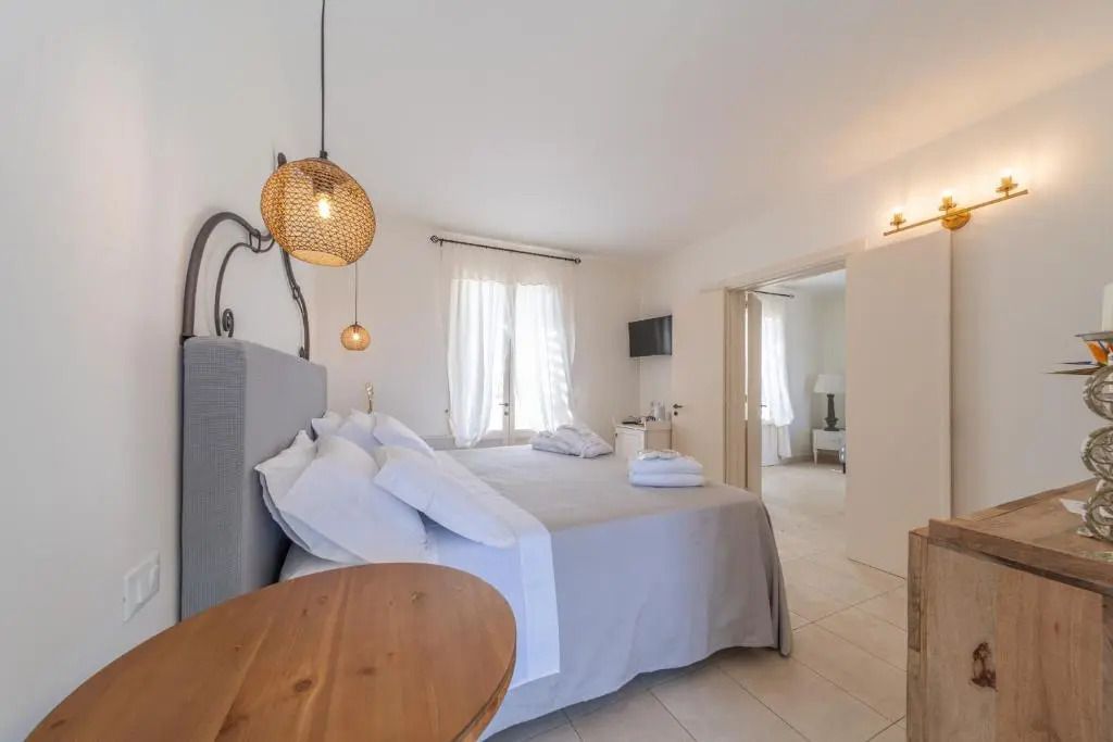Helles Schlafzimmer mit Doppelbett, weißer Bettwäsche und Hängelampe