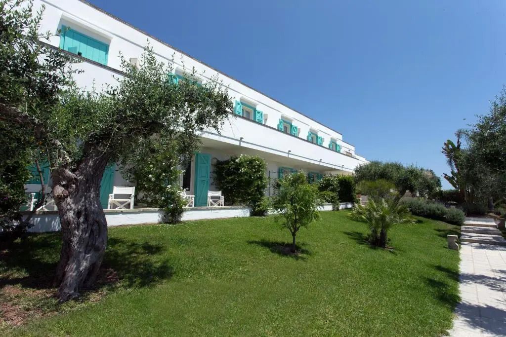 Außenansicht des Hotels mit gepflegtem Garten und mediterraner Architektur.