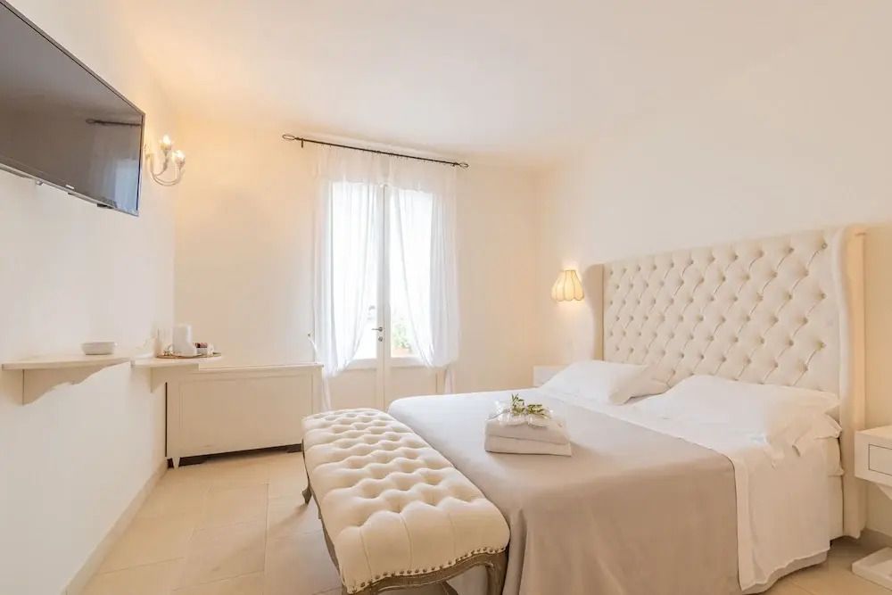 Elegantes Schlafzimmer mit gepolstertem Kopfteil und Sitzbank in der Tenuta Centoporte.
